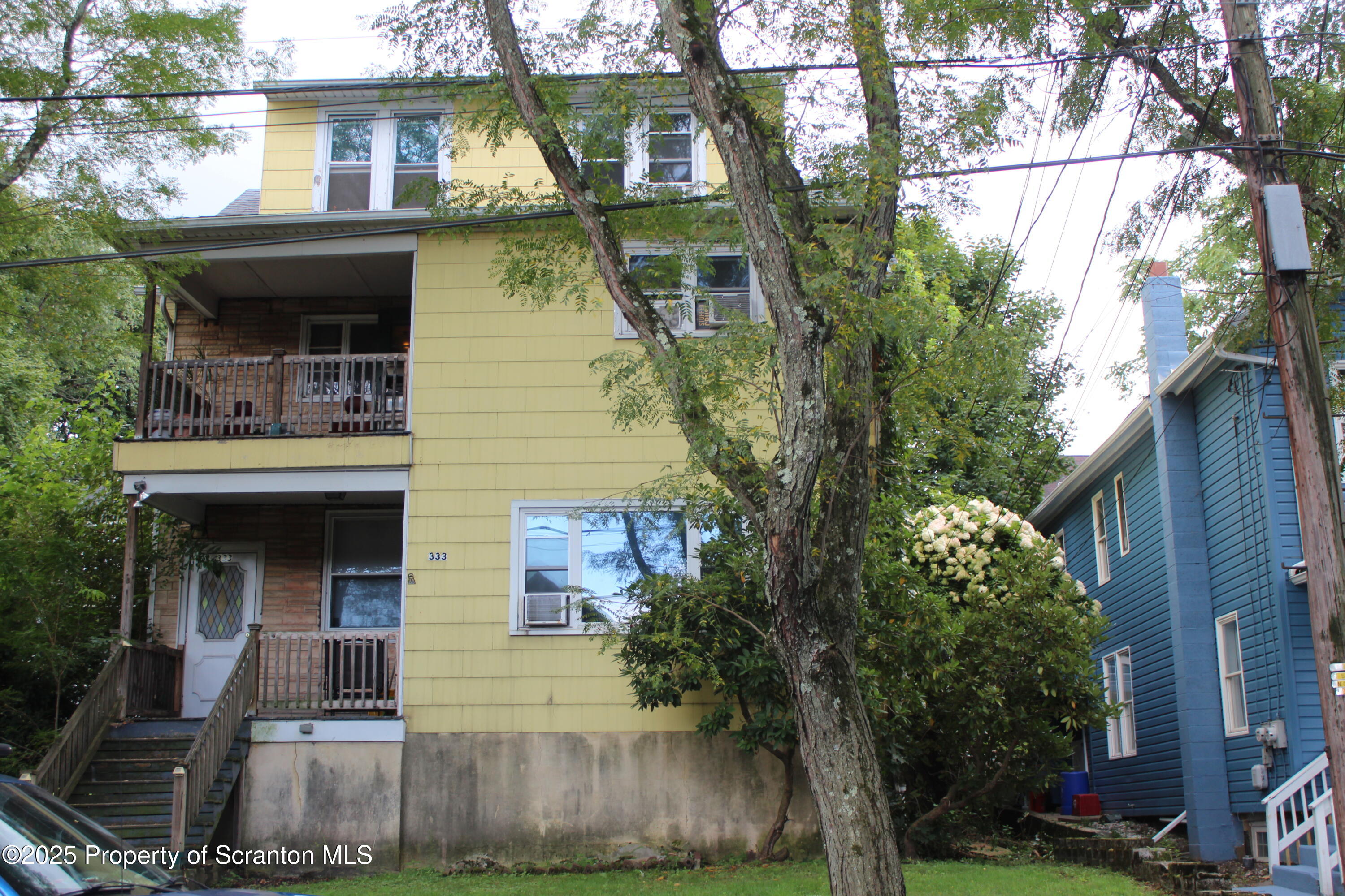 a view of a white house with large windows and a tree