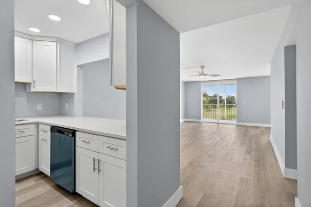 a kitchen with white cabinets and wooden floor