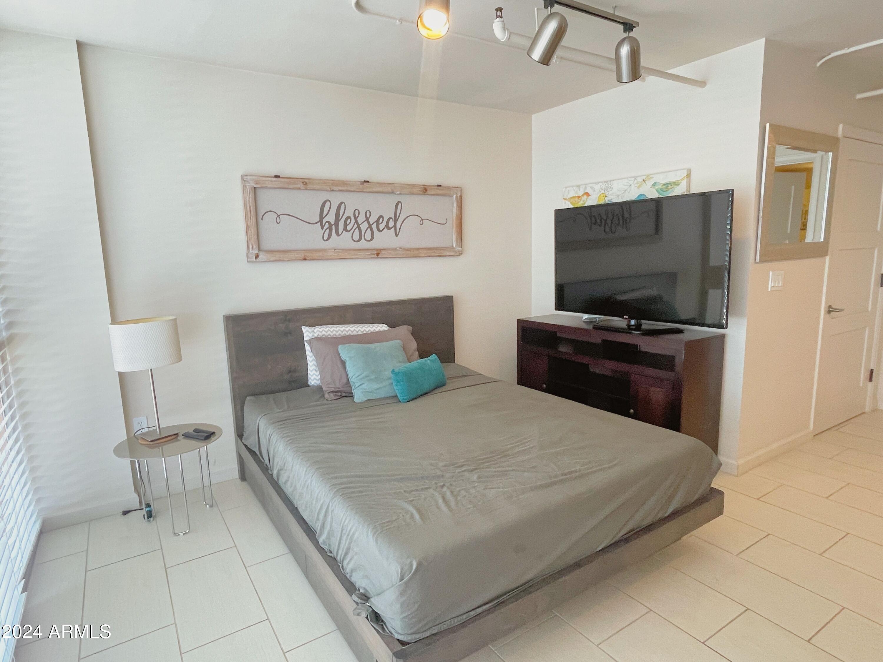 535 West Thomas Road, Unit 401 Phoenix, AZ 85013 - Photo 9 of 22 a bedroom with a bed and a flat screen tv