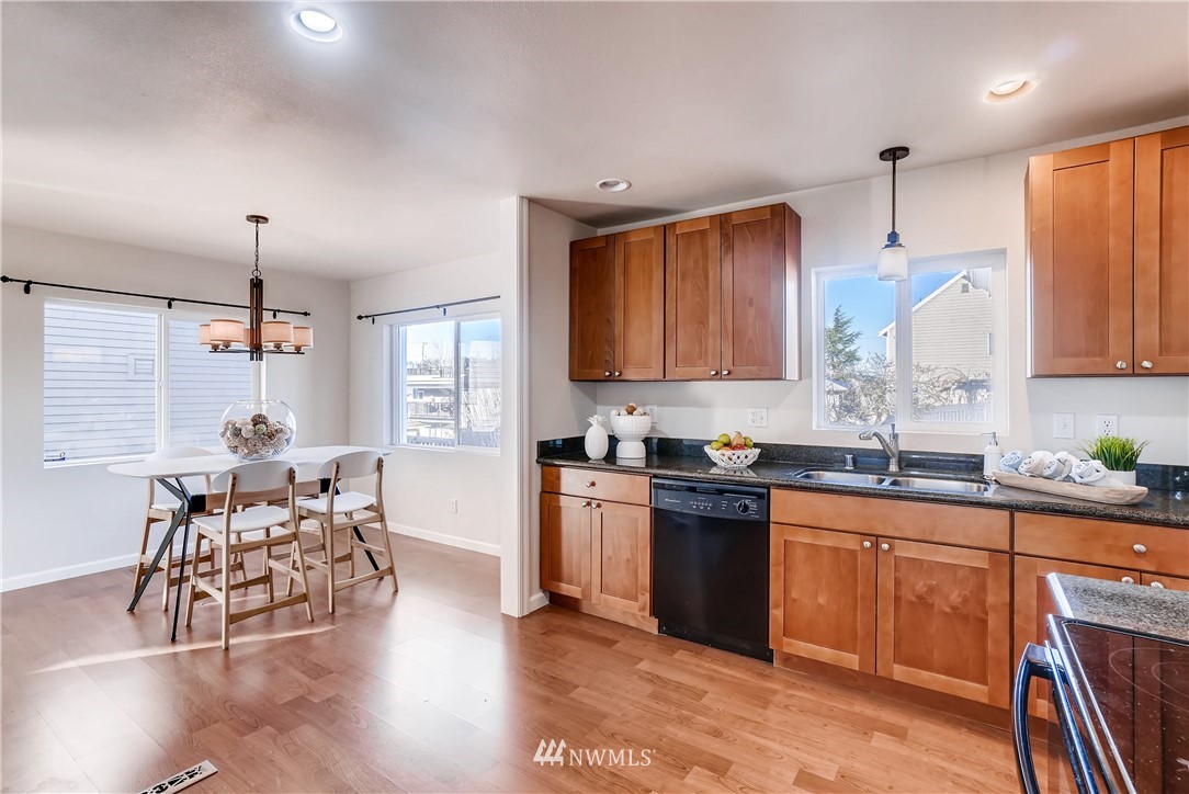 718 North 30th Street Renton, WA 98056 - Photo 8 of 21 a kitchen with granite countertop a stove a sink a dining table and chairs with wooden floor