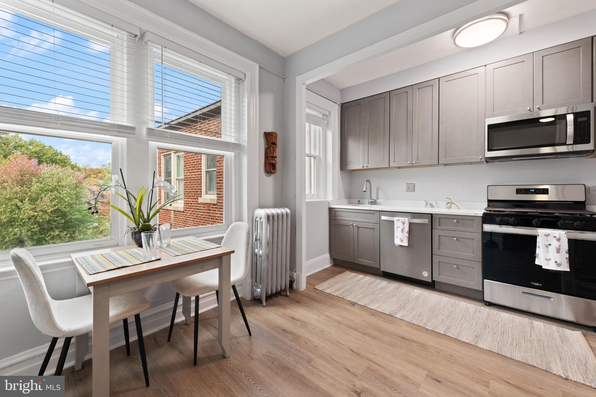 2456 20th Street Northwest, Unit 507 Washington, DC 20009 - Photo 20 of 42 a kitchen with stainless steel appliances a stove a sink dishwasher a microwave oven with a dining table and chairs