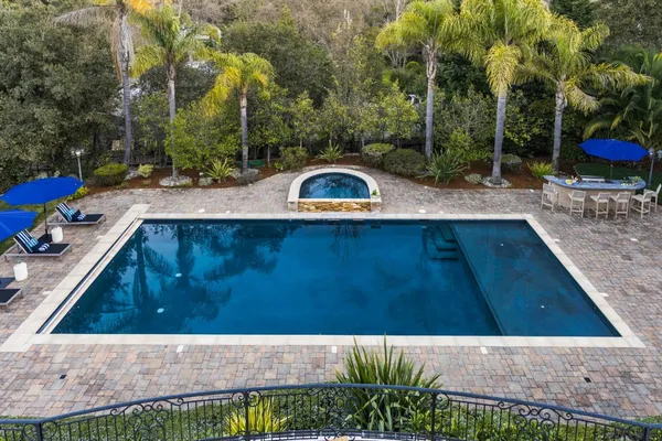 a view of a swimming pool with a bench and trees around