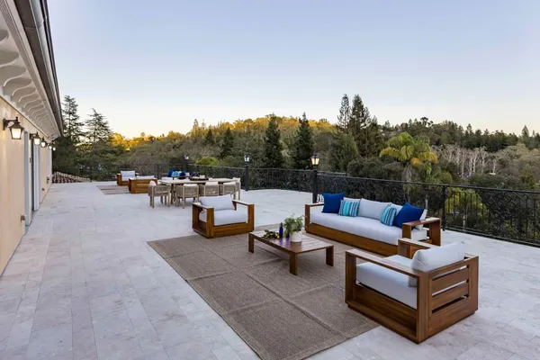 a view of a roof deck with couches and wooden fence