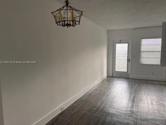 an empty room with wooden floor cabinet and windows