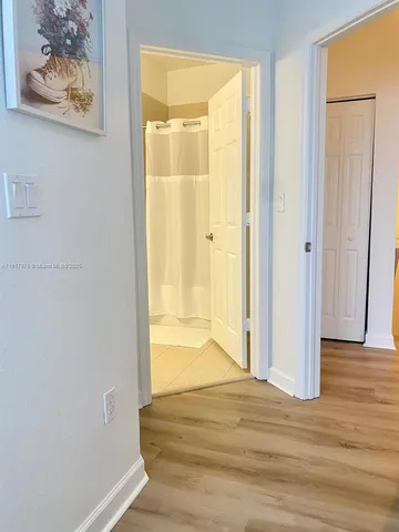 a view of a hallway with wooden floor and a bathroom