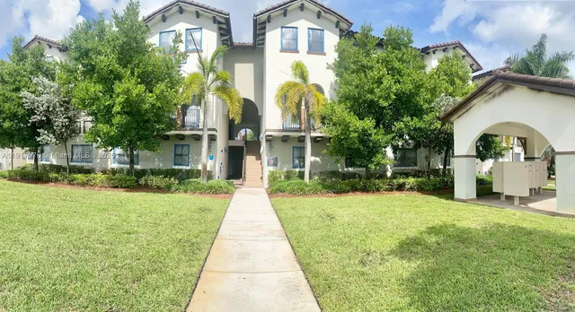 a front view of a house with a yard and potted plants