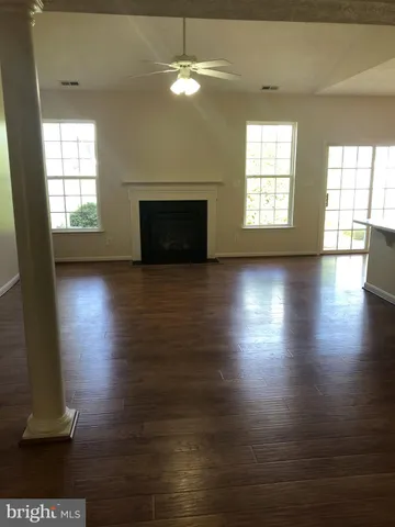 an empty room with wooden floor fireplace and windows