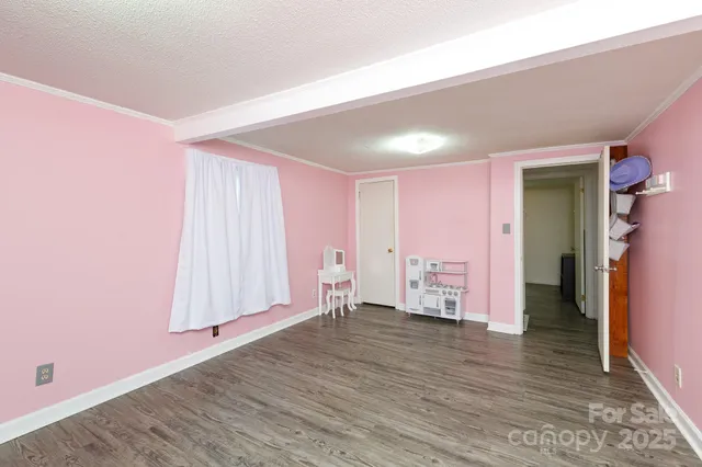a view of an empty room with wooden floor and closet