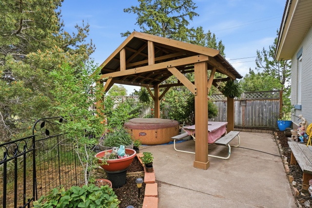 5264 West 5500th Street South Hooper, UT 84315 - Photo 27 of 38 Concrete patio featuring a wood-frame gazebo, hot tub, and surrounding mature greenery