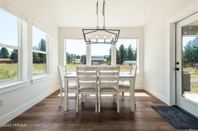 a dining room with wooden floor a chandelier a glass table and chairs