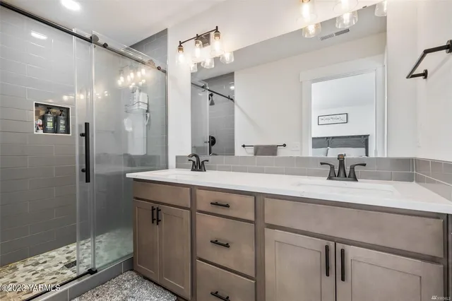 a bathroom with a double vanity sink a mirror and shower