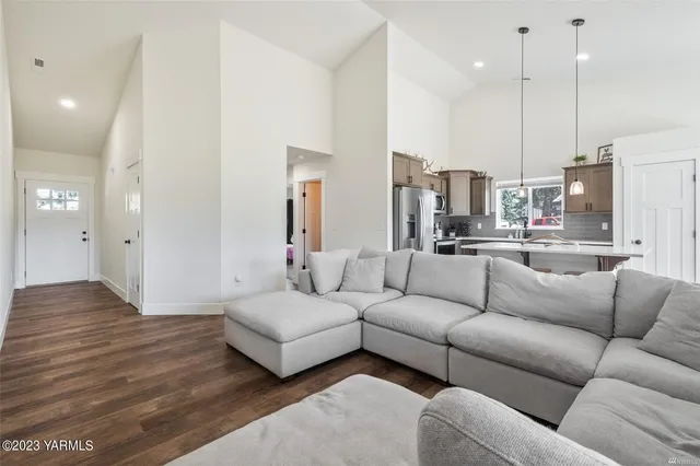 a living room with furniture kitchen view and a wooden floor