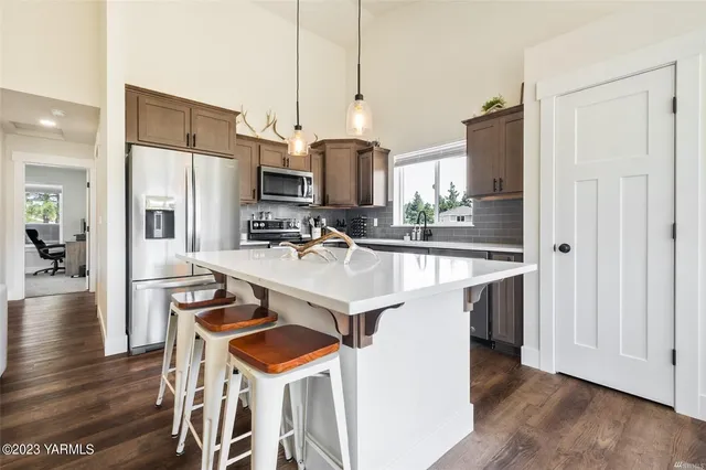 a kitchen with a sink a kitchen island a stove a refrigerator and a dining table with wooden floor