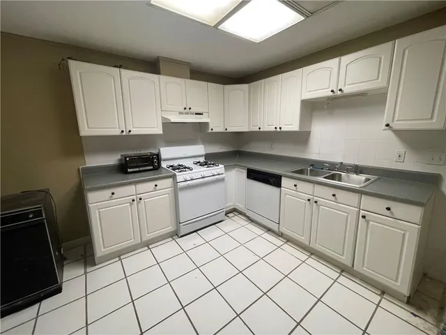 a kitchen with white cabinets appliances and a sink