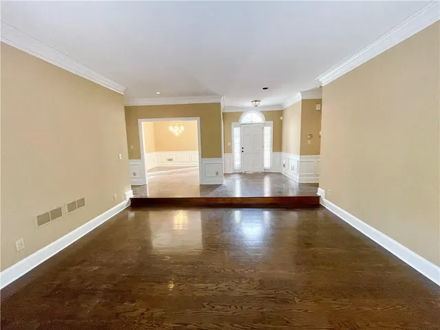a view of an empty room with window and wooden floor