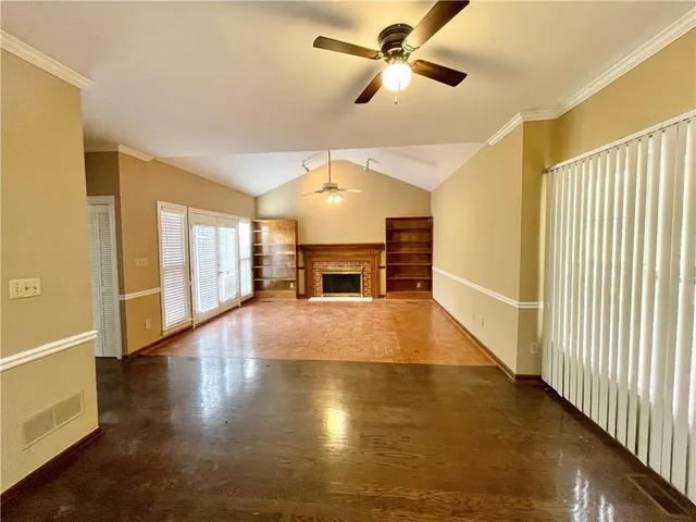 a view of a livingroom with wooden floor a ceiling fan and windows