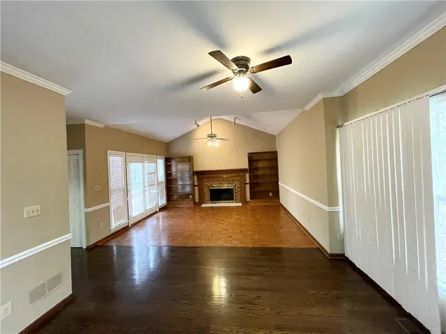 a view of an empty room with wooden floor fireplace and a window