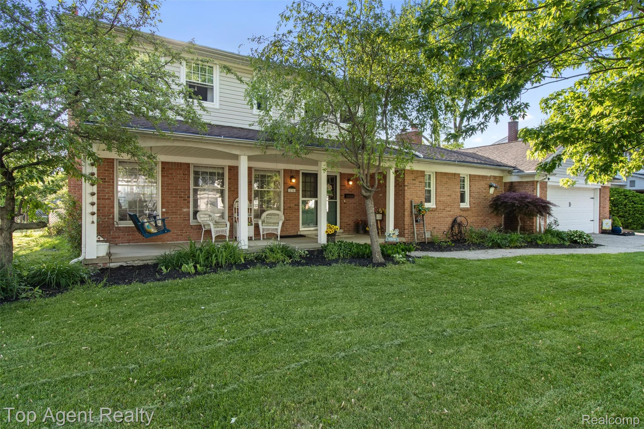 32341 Woody Road Fraser, MI 48026 - Photo 42 of 47 Brick and siding exterior featuring a covered front porch, white columns, a manicured lawn, an attached garage, and mature trees