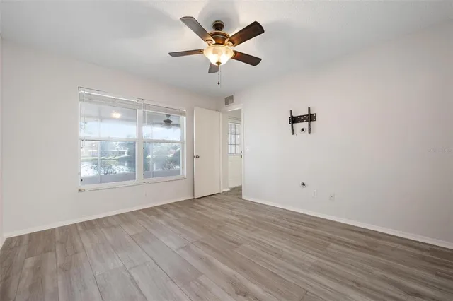 an empty room with wooden floor and windows