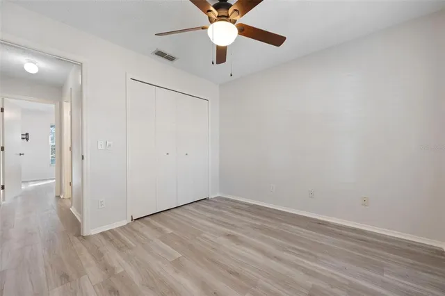 an empty room with wooden floor a ceiling fan and closet