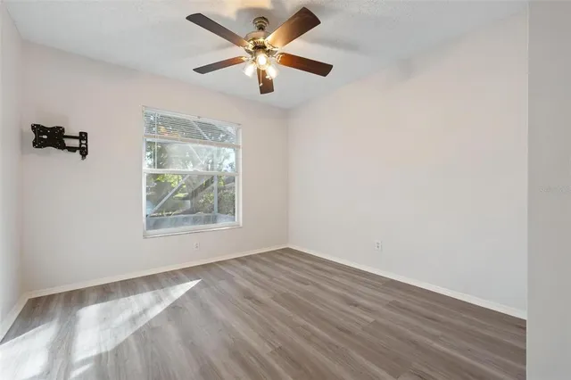 an empty room with wooden floor fan and windows