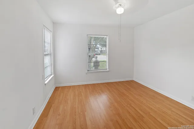 an empty room with windows and fan