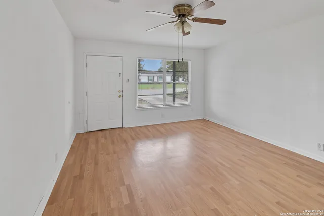 a view of empty room with wooden floor and window