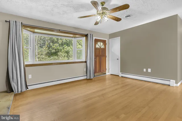 an empty room with windows and ceiling fan