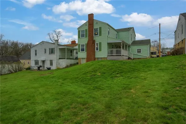 a view of a big house with a big yard and large trees