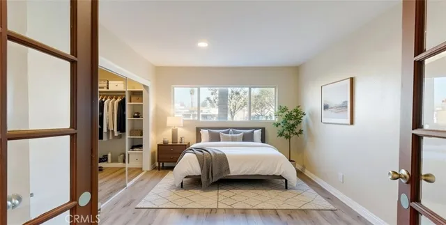 a bedroom with a bed wooden floor and a large window