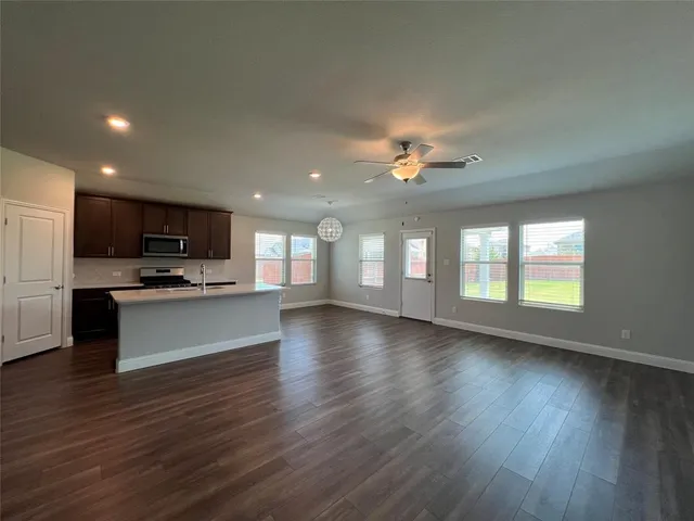 an open kitchen with refrigerator and a stove top oven