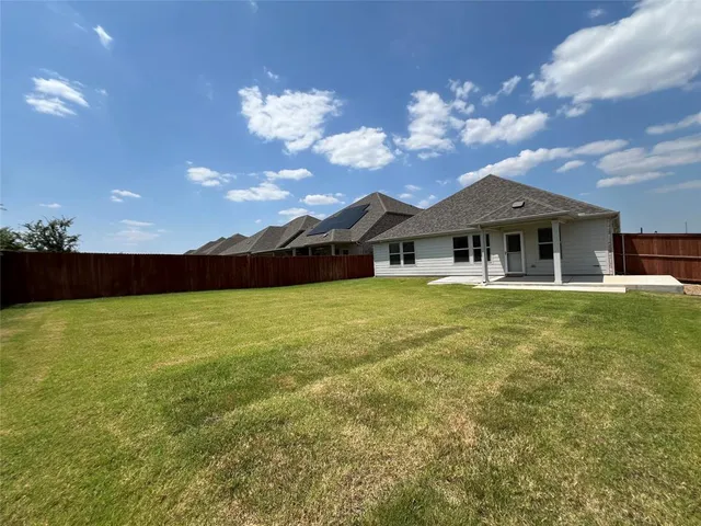 a view of a house with big yard plants and large tree