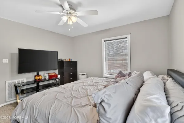 a bedroom with a bed and a flat tv screen on dresser