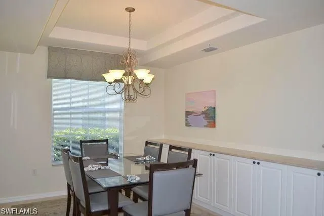 a dining room with wooden floor a chandelier a wooden table and chairs