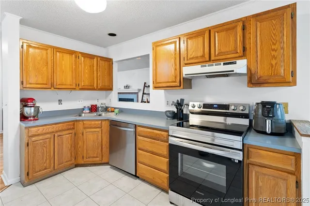 a kitchen with stainless steel appliances granite countertop wooden cabinets a stove a sink and a window