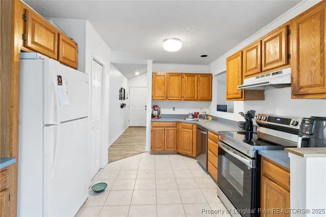 a kitchen with stainless steel appliances granite countertop a refrigerator and a stove top oven