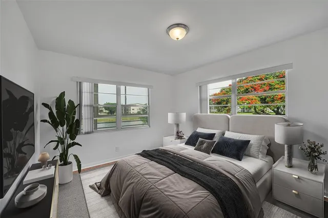 a bedroom with a bed and large windows