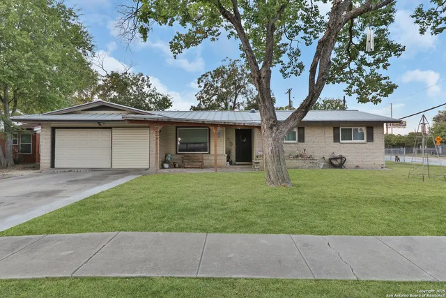 a front view of a house with a garden and trees