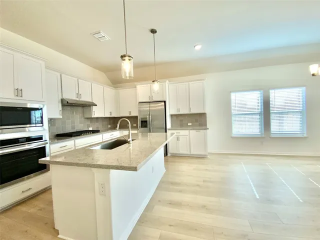 a view of a hallway with wooden floor and a bathroom