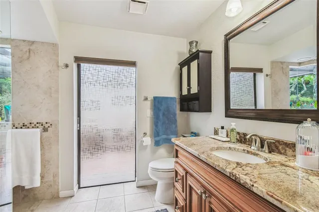 a bathroom with a granite countertop sink a toilet and a mirror