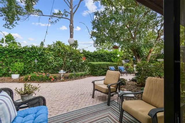 a view of a patio with table and chairs and potted plants with large tree