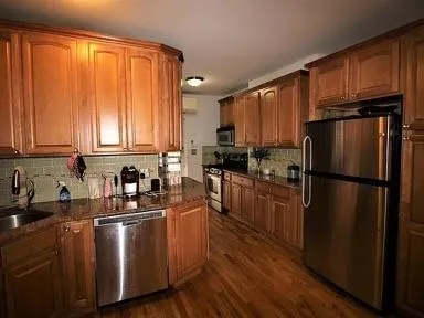 a kitchen with a refrigerator a sink dishwasher and wooden cabinets with wooden floor