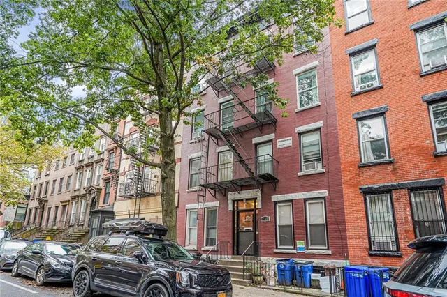 a front view of a building with lot of cars parked on road
