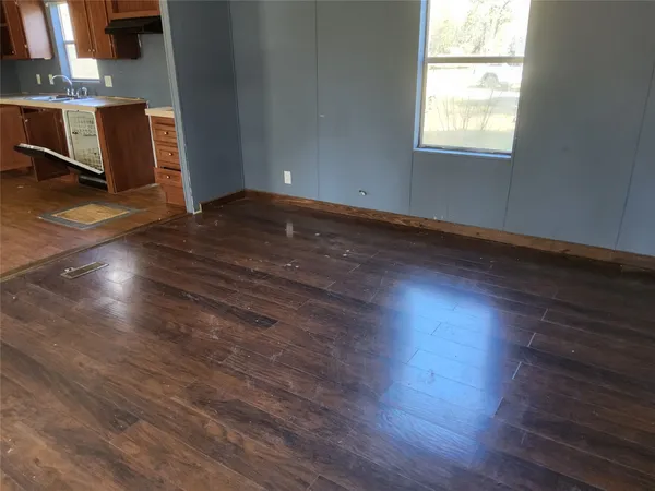 an empty room with wooden floor a fireplace and windows