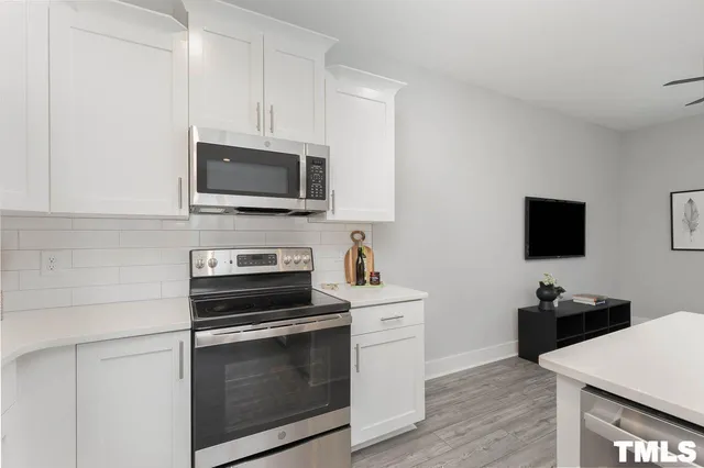 a kitchen with cabinets stainless steel appliances and wooden floor