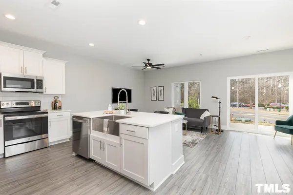 a open kitchen with a stove a sink dishwasher and a microwave oven with wooden floor