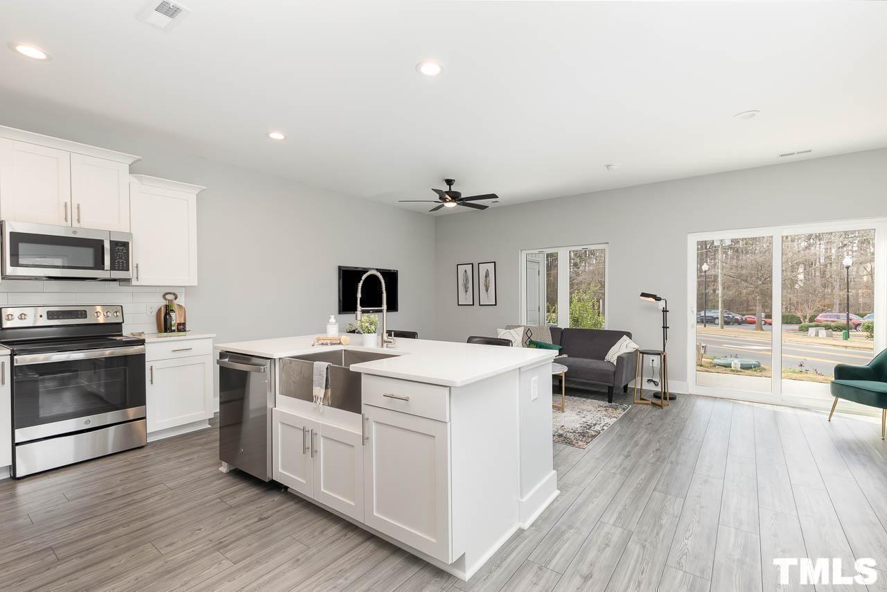 4 South Laird Drive, Unit 7 Clayton, NC 27520 - Photo 8 of 26 a open kitchen with a stove a sink dishwasher and a microwave oven with wooden floor