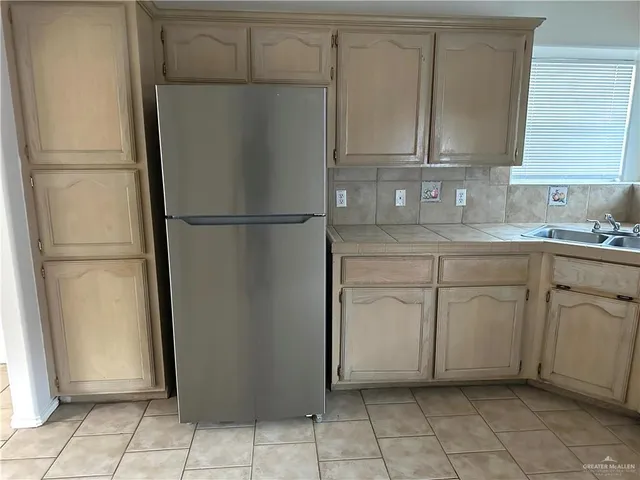 a kitchen with white cabinets and refrigerator