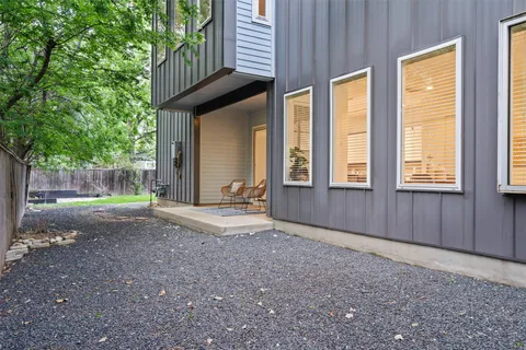 a view of backyard with large trees and wooden fence