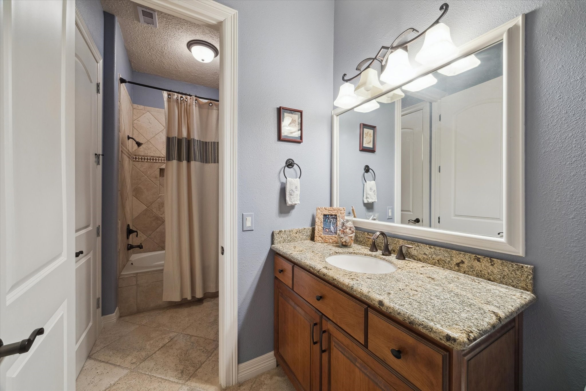 1406 Todville Road Seabrook, TX 77586 - Photo 29 of 49 1ST LEVEL BATH WITH GRANITE COUNTERS, FRAMED MIRROR AND A TUB/SHOWER WITH TILE SURROUND.